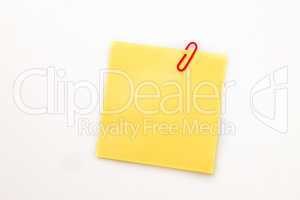 Yellow adhesive note with a paperclip