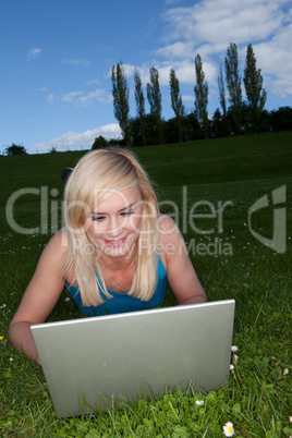 Smiling woman using a laptop in the park