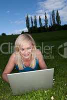 Smiling woman using a laptop in the park