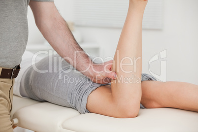 Woman lying forward while a physiotherapist bends her leg