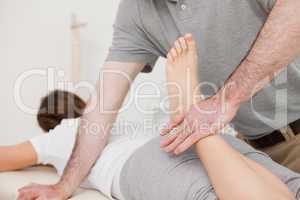 Physiotherapist bending the leg of his peaceful patient