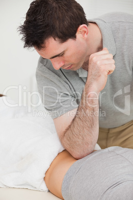 Physiotherapist massaging the back of a woman with his elbow