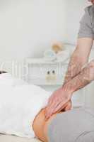 Woman lying while a physiotherapist is massaging her back