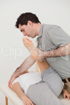 Woman lying while a physio moving her leg