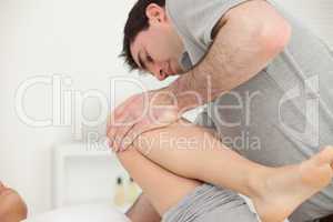 Woman lying while a physiotherapist folded her leg on her chest