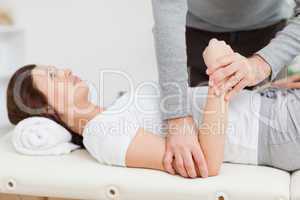 Physiotherapist manipulating the arm of a peaceful woman