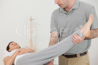 Brunette woman lying while a therapist is stretching her leg