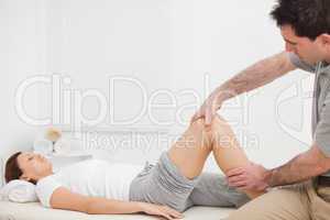 Brunette woman lying while a physiotherapist manipulates her leg