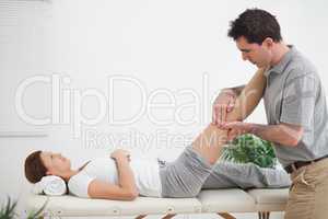 Physiotherapist massaging a leg while placing it on his shoulder