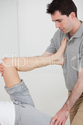 Physiotherapist stretching a leg while placed it on his chest