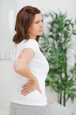 Woman touching her back while looking away