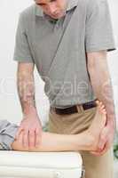 Serious physiotherapist stretching the leg of a patient
