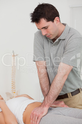 Serious physiotherapist manipulating the pelvis of a patient