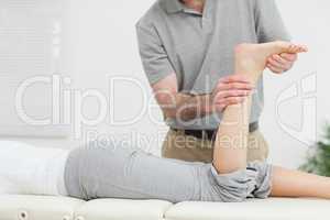 Woman lying forward while a physiotherapist examining her leg