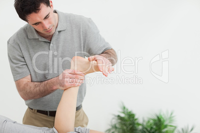 Brown-haired therapist stretching the foot of a patient