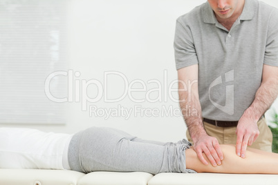 Woman lying forward while a physiotherapist massaging her leg