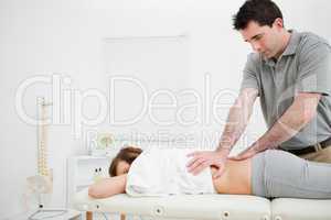 Serious practitioner massaging the lower back of a woman