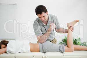 Woman lying forward while a man stretched her leg