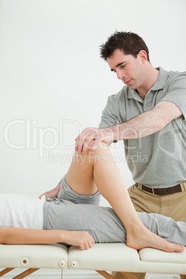 Serious physiotherapist stretching a leg while standing