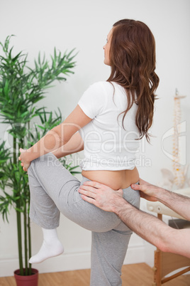 Woman stretching her leg while a man is touching her back