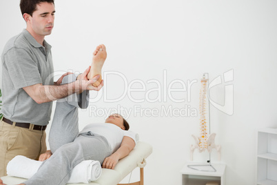 Brunette physiotherapist manipulating the leg of a woman