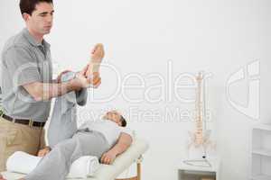 Brunette physiotherapist manipulating the leg of a woman