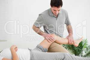 Masseur massaging the leg of a woman while placing it on his thi