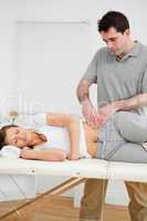 Serious physiotherapist checking the pelvis of a woman
