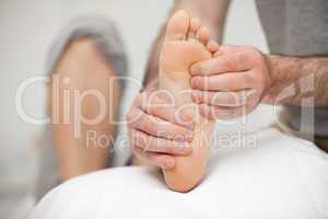 Chiropodist palpating the sole of the foot of a patient