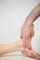Two fingers pressing the Achilles tendon of a patient