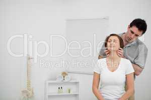 Serious osteopath palpating the neck of a woman