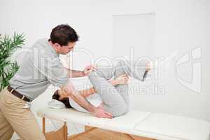 Physiotherapist pushing the leg of a woman on the side