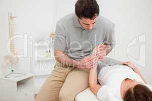 Serious physiotherapist holding the hand of a woman