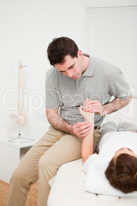 Serious physiotherapist moving the wrist of a woman
