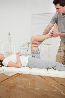 Serious osteopath bending the leg of a woman