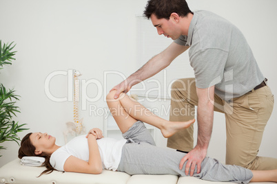 Serious doctor stretching the leg of a woman