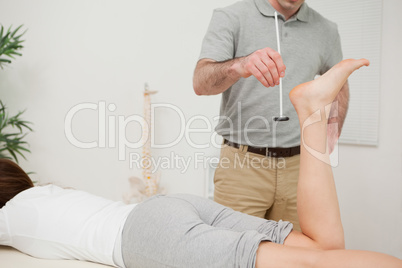 Serious doctor using a reflex hammer on his patient