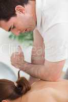 Back of woman being massaged by the elbow of doctor