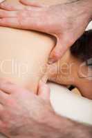 Chiropractor massaging the shoulders of his patient while using