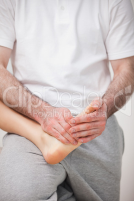 Podiatrist manipulating the foot of a woman while holding it on