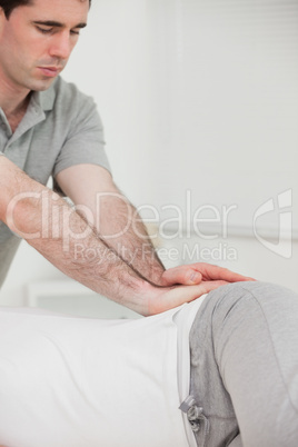 Serious chiropractor pressing the hip of his patient