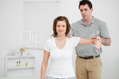 Doctor examining the shoulder of his patient while holding his a