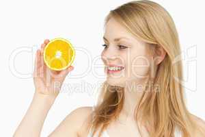 Joyful woman presenting an orange while looking at it