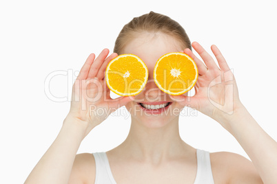 Smiling woman placing oranges on her eyes