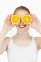 Cheerful woman placing oranges on her eyes