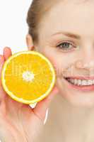 Close up of a smiling woman holding an orange