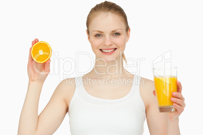 Woman holding a glass while presenting an orange