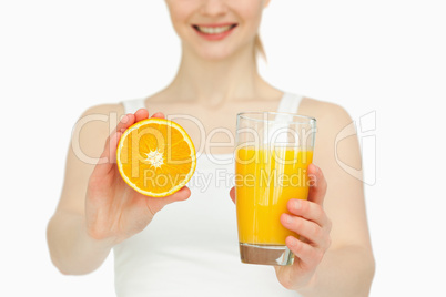 Woman presenting an orange while holding a glass