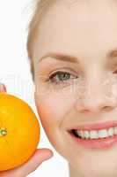 Close up of a cheerful woman holding an orange