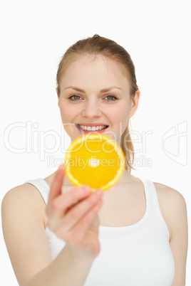 Smiling woman presenting a slice of orange